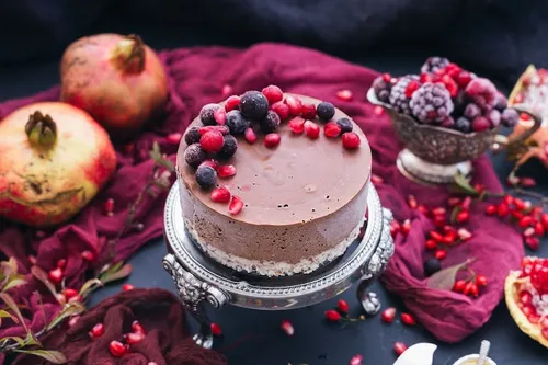 Pink berry cake surrounded by pomegranate and berries